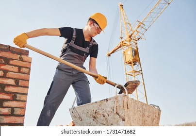 Using showel. Construction worker in uniform and safety equipment have job on building.