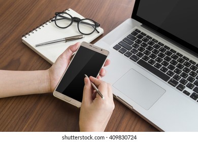 Using smart phone with pen tablet and notebook computer on wooden table.