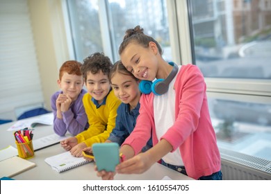 Using smartphone during the break. The group of children making selfie at school - Powered by Shutterstock