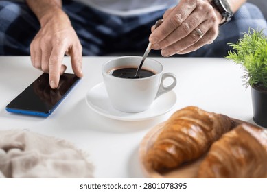 Using Smartphone During Breakfast with Coffee and Croissants on White Table