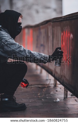 Using spray paint can to make protest sign. Charismatic man with hidden identity makes vandalism.
