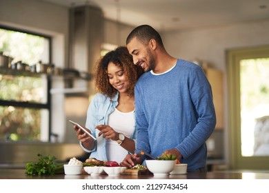 Using a step by step online recipe. Shot of a happy young couple using a digital tablet while preparing a healthy meal together at home. - Powered by Shutterstock