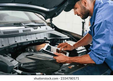 Using tablet. Auto mechanic working in garage. Repair service. - Powered by Shutterstock