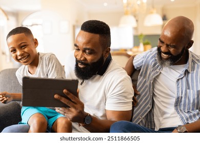 Using tablet, father and grandfather entertaining happy child on couch at home. Family, bonding, technology, intergenerational, happiness, leisure - Powered by Shutterstock