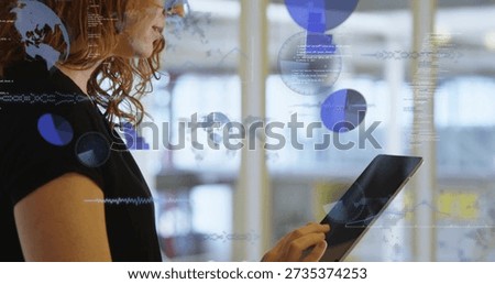Using tablet, female tech in black top interacting with data overlays in office, copy space. Woman, analytics, ar, visualization, worldmap, piechart, waveform