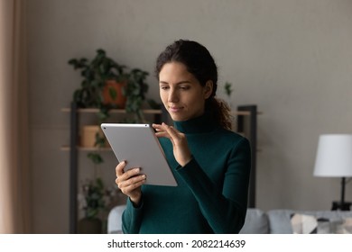 Using tablet pc. Confident user young latin female scroll web pages on wide screen of pad device read business message on modern gadget. Millennial hispanic woman engaged in distant learning on tab - Shutterstock ID 2082214639
