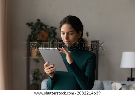 Using tablet pc. Confident user young latin female scroll web pages on wide screen of pad device read business message on modern gadget. Millennial hispanic woman engaged in distant learning on tab