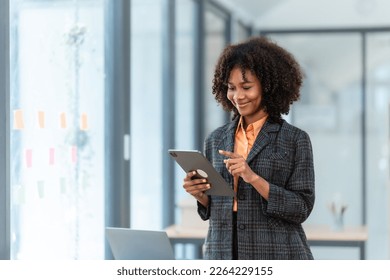 Using tablet pc, Young pretty african american business woman bookkeepers working with balance sheet yearly reports to calculate tax and online consult in modern office. - Powered by Shutterstock