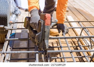 Using this tool, workers twist reinforcement wires with steel bars for cement foundations in construction site