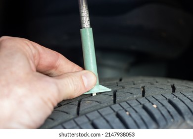 Using A Tire Gauge To Check Tread Depth On A Tire