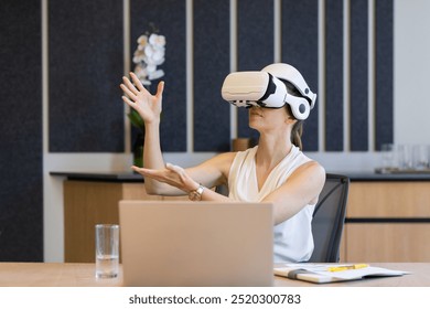 Using VR headset, businesswoman interacting with virtual environment at office desk. Technology, innovation, virtual reality, workspace, interaction, corporate - Powered by Shutterstock