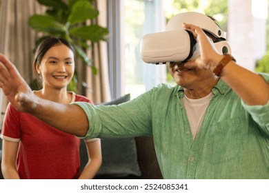 Using VR headset, father interacting with virtual environment while daughter watching. Technology, virtual reality, interaction, immersive, digital, observing - Powered by Shutterstock