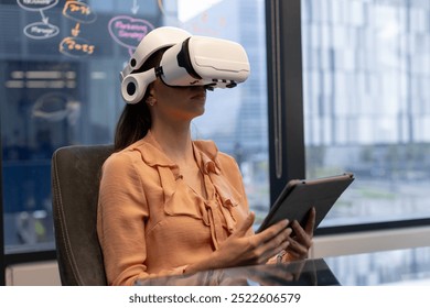 Using VR headset and holding tablet, woman working in modern office. Technology, business, virtual reality, remote working, innovation, digital