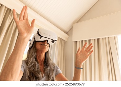 Using VR headset, mature woman experiencing virtual reality at home. technology, immersive, experience, gadget, entertainment, interactive - Powered by Shutterstock