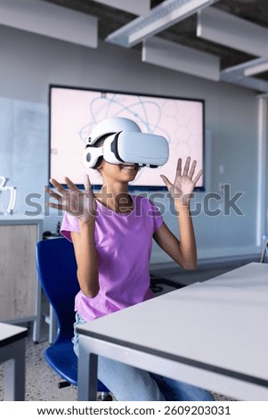Using VR headset, student in school classroom experiencing virtual reality. Technology, education, learning, innovation, interactive, students