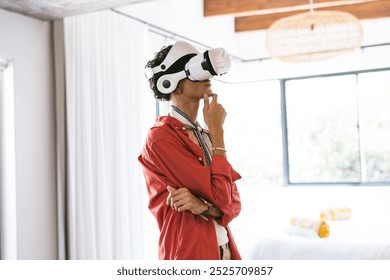 Using VR headset, young man in red shirt thinking in modern home setting. Virtual reality, technology, innovation, futuristic, experience, immersive - Powered by Shutterstock