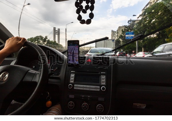 Using waze\
maps application on smartphone on car dashboard, Driver using maps\
app for showing the right route through the traffic of city on a\
rainy evening. Bucharest, Romania,\
2020.