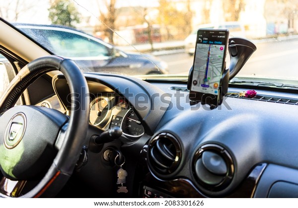Using waze maps application on\
smartphone in car dashboard. Driver using maps app for showing the\
right route through the traffic in Bucharest, Romania,\
2021