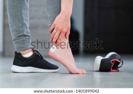 Using white medical sticking plaster from calluses during wearing a new shoe. Skin care feet and prevention of calluses and corns