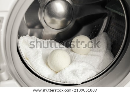 Using wool dryer balls for more soft clothes while tumble drying in washing machine concept. Discharge static electricity and shorten drying time, save energy.