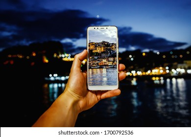 Using your smartphone as a mobile camera while traveling. Tourist city at dusk on screen