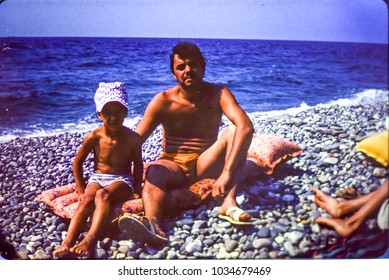 USSR, ABKHAZIA, BLACK SEA - CIRCA 1980: Vintage Family Photo Of Father With Little Son On Black Sea Beach