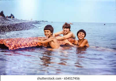 USSR, ABKHAZIA, LESELIDZE - CIRCA 1981: Vintage Family Photo Of Mother With Children Laughing In Black Sea Water At Beach Landscape