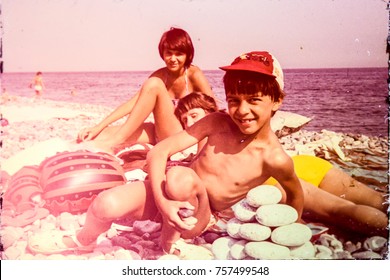 USSR, ABKHAZIA, LESELIDZE VILLAGE - CIRCA 1982: Vintage Family Photo Of Mom With Kids On Pebble Beach At Black Sea