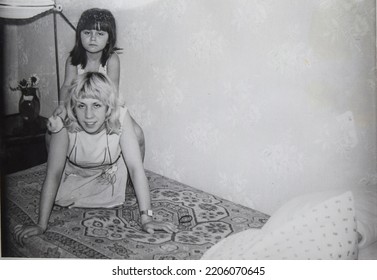 USSR, LENINGRAD - CIRCA 1974: Vintage Family Photo Of Young Mom And Daughter Fool Around And Play At Home