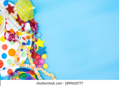 Utensils for children's birthdayparties and parties such as smarties, umbrellas and mugs on a blue background. Horizontal