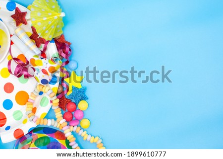 Utensils for children's birthdayparties and parties such as smarties, umbrellas and mugs on a blue background. Horizontal