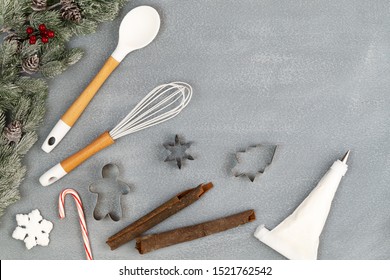 Utensils And Spice For Christmas Cooking Or Baking With Spoon, Whisk, Cookie Cutters, Icing Piping Bag, Cinnamon Sticks, Candy Cane And Snow Flake Over Concrete Background, Copy Space, Top View.