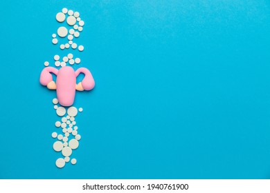 Uterus with ovaries on a blue background with pills. Female reproductive system model. Copy space for text.