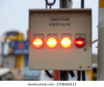 A utility box is seen with multiple indicators lit up and glowing, in an industrial setting with a blurred background.