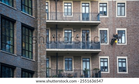 utility climber on the rope while washing the windows of a building outside.