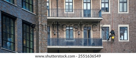utility climber on the rope while washing the windows of a building outside.