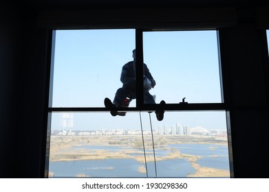 Utility climber while washing the windows of a glass building.