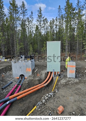 Utility Conduits Terminated at Vaults and Electrical Kiosk. Multiple colored conduits feeding into utility vaults and pad-mounted electrical kiosk at forested site.