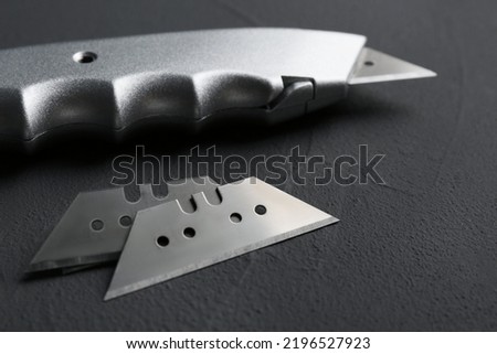 Utility knife and blades on black background, closeup