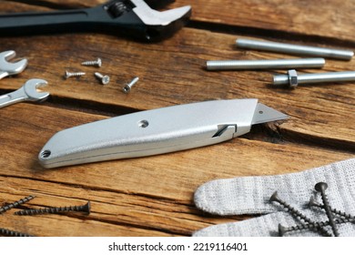 Utility knife and different tools on wooden table