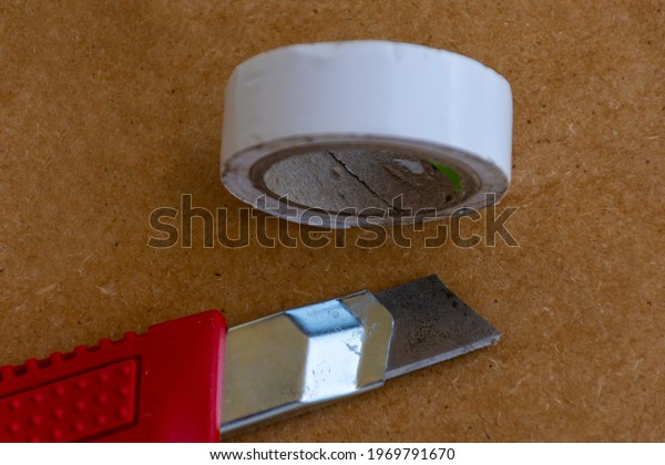 utility\
knife and white electrical tape on\
chipboard