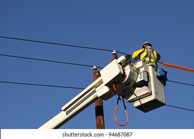 Utility Lineman Working On Cables Against Blue Sky