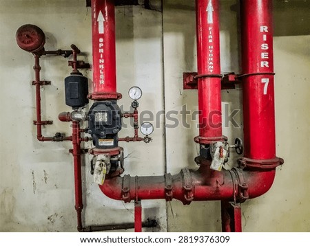 Utility piping controls, consisting of a network of red pipes for sprinkler systems and fire hydrant risers in a building.