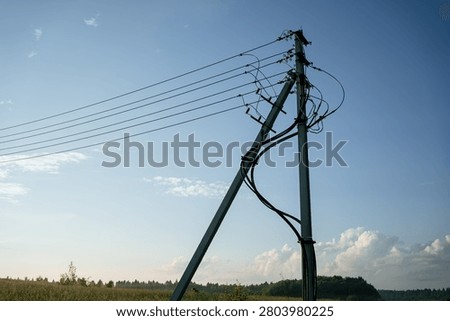 Utility pole standing tall, featuring insulators and numerous power lines extending across the open field, distributing electricity and essential services to remote areas