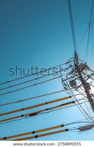 Utility pole with transformers and power lines against clear blue sky