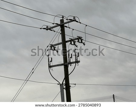 Utility power infrastructure beneath dramatic overcast sky showing electrical transmission lines and moody outdoor energy network scene