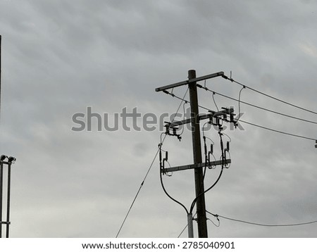 Utility power infrastructure beneath dramatic overcast sky showing electrical transmission lines and moody outdoor energy network scene