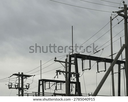 Utility power infrastructure beneath dramatic overcast sky showing electrical transmission lines and moody outdoor energy network scene