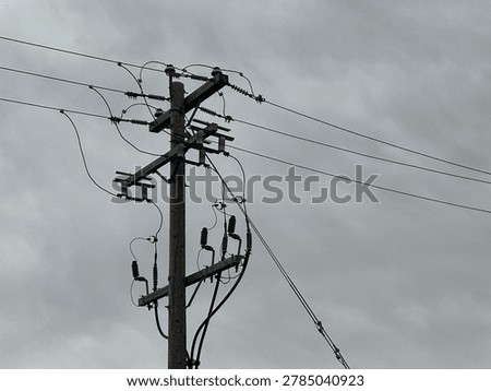 Utility power infrastructure beneath dramatic overcast sky showing electrical transmission lines and moody outdoor energy network scene