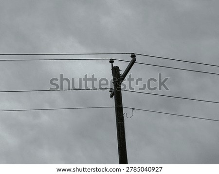 Utility power infrastructure beneath dramatic overcast sky showing electrical transmission lines and moody outdoor energy network scene